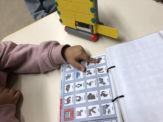 Fillette pointant un picto sur son cahier de communication