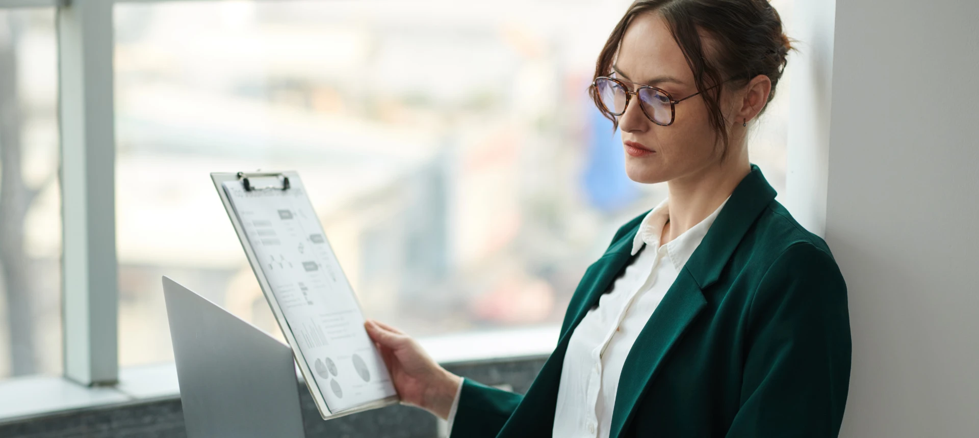 Une femme en tailleur vert tient un bloc note