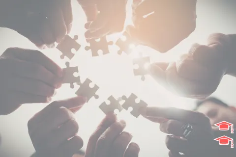 Des personnes tiennent des pièces de puzzle dans leur mains avec une vue par le bas montrant alors le ciel ensoleillé en arrière plan