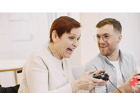 Une personne en fauteuil roulant joue au jeux vidéo avec une autre personne